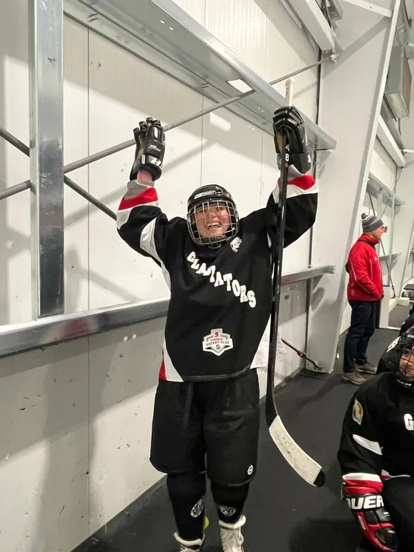 A Gladiators player raising both arms in celebration at the rink